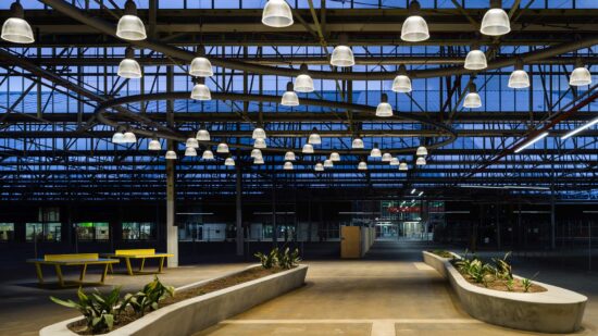 Bright yellow ping pong tables and befitting industrial light fixtures provide fun accents to the Tonsley Main Assembly Building and Pods mixed-use project in Clovelly Park, Australia. (Image courtesy Woods Bagot) 