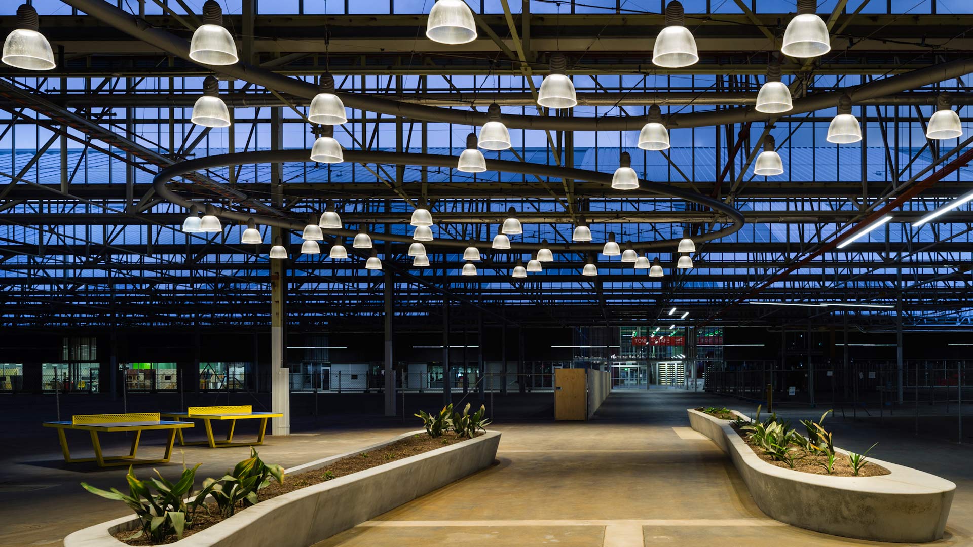 Bright yellow ping pong tables and befitting industrial light fixtures provide fun accents to the Tonsley Main Assembly Building and Pods mixed-use project in Clovelly Park, Australia. (Image courtesy Woods Bagot)